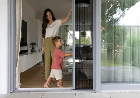 Insektenschutz-Schiebetür für einen komfortablen Zugang zur Terrasse Mutter und Kind an einer Terrassentür mit Insektenschutz-Schiebetür